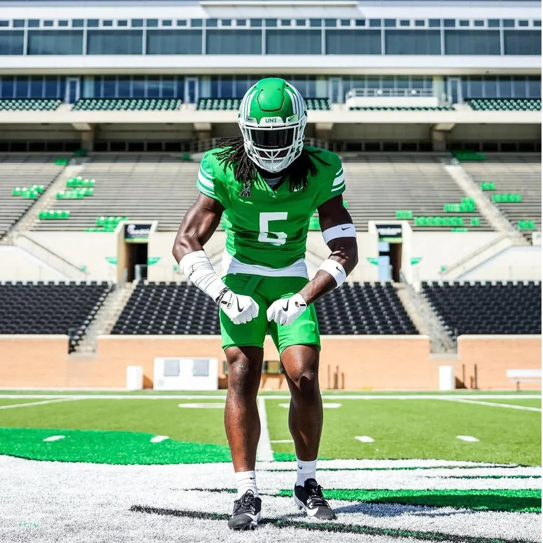 Football player in green UNT uniform on field, ready for action